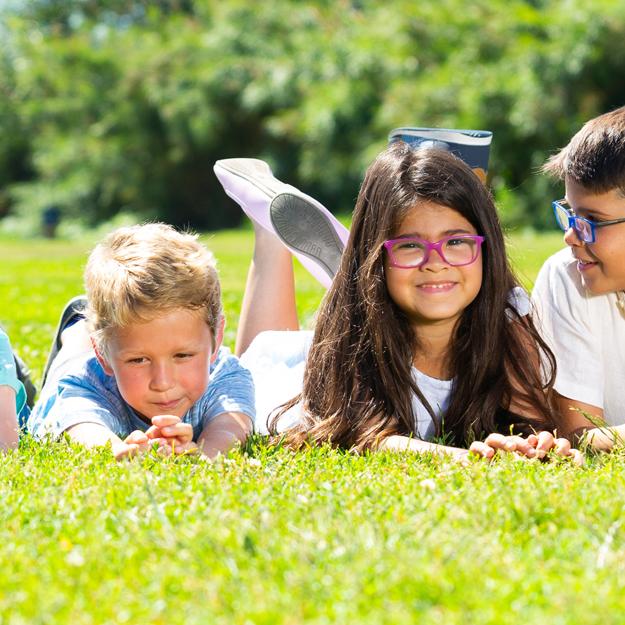 Happy team of friends children resting on grass together in park